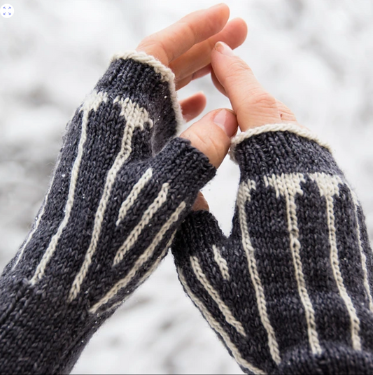 the hands of a white human are cozy inside natural brown knitted fingerless mitts with undyed white pinstripe accents. This is set against a snowy white background