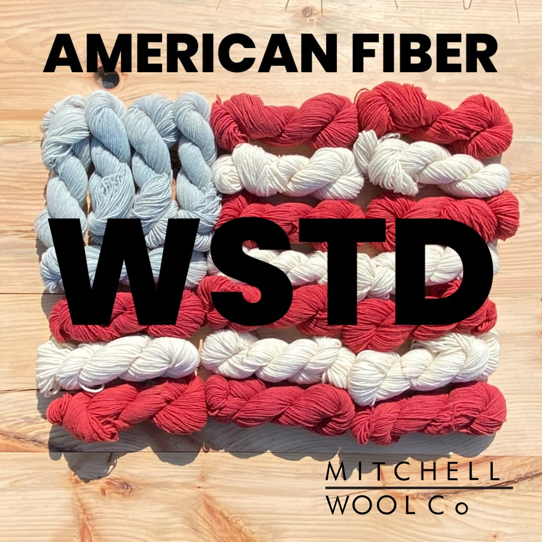 an American flag composed of yarn with the words American Fiber wstd in black on the surfaces.