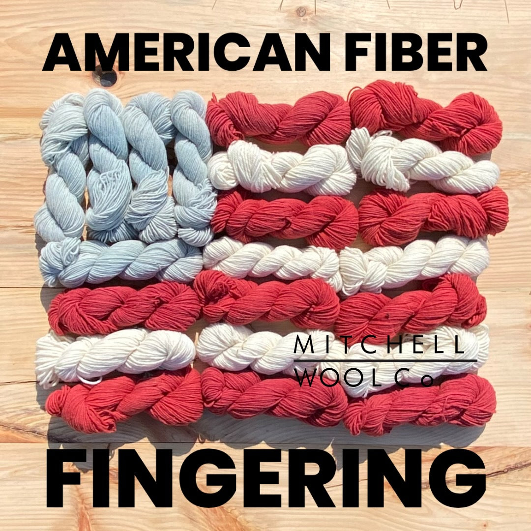 an American flag composed of yarn with the words American Fiber Fingering in black on the surfaces.