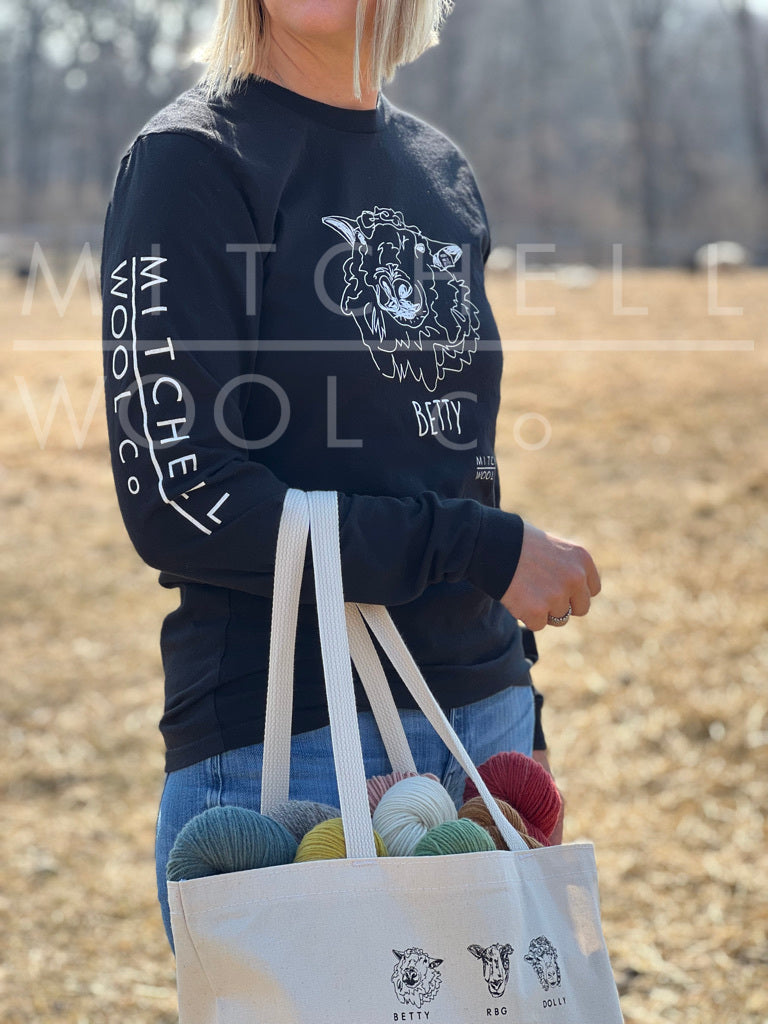 Sherry stands in the mama ewes pasture on a warm early spring day holding our organic cotton "know your wool" tote. She knows it very well, those mamas keep her up at night. Oh right, the shirt- It's a black organic cotton shirt with a sketch of our Big Better on the front, and Mitchell Wool logo down the right sleeve.