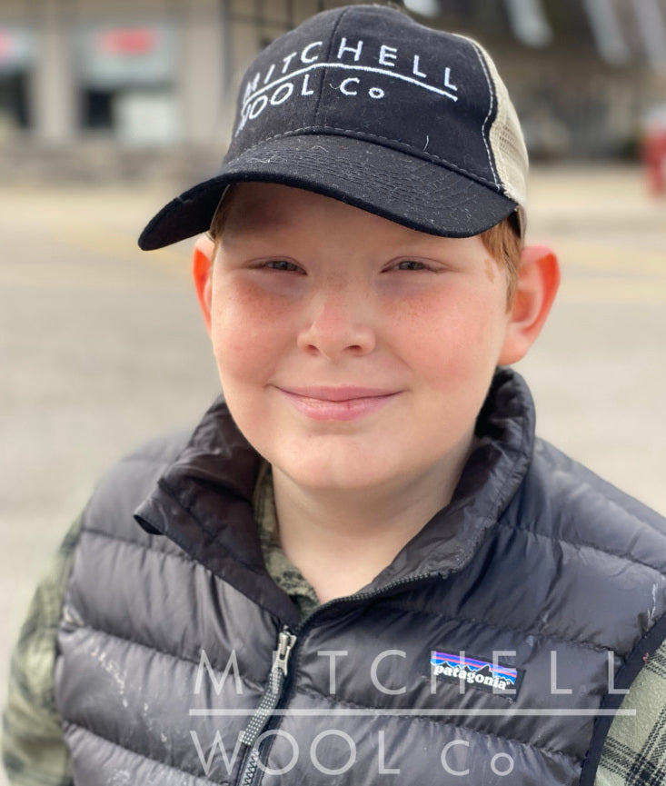 Future farmer grins and squints in the sunshine while wearing his beloved MWC trucker hat
