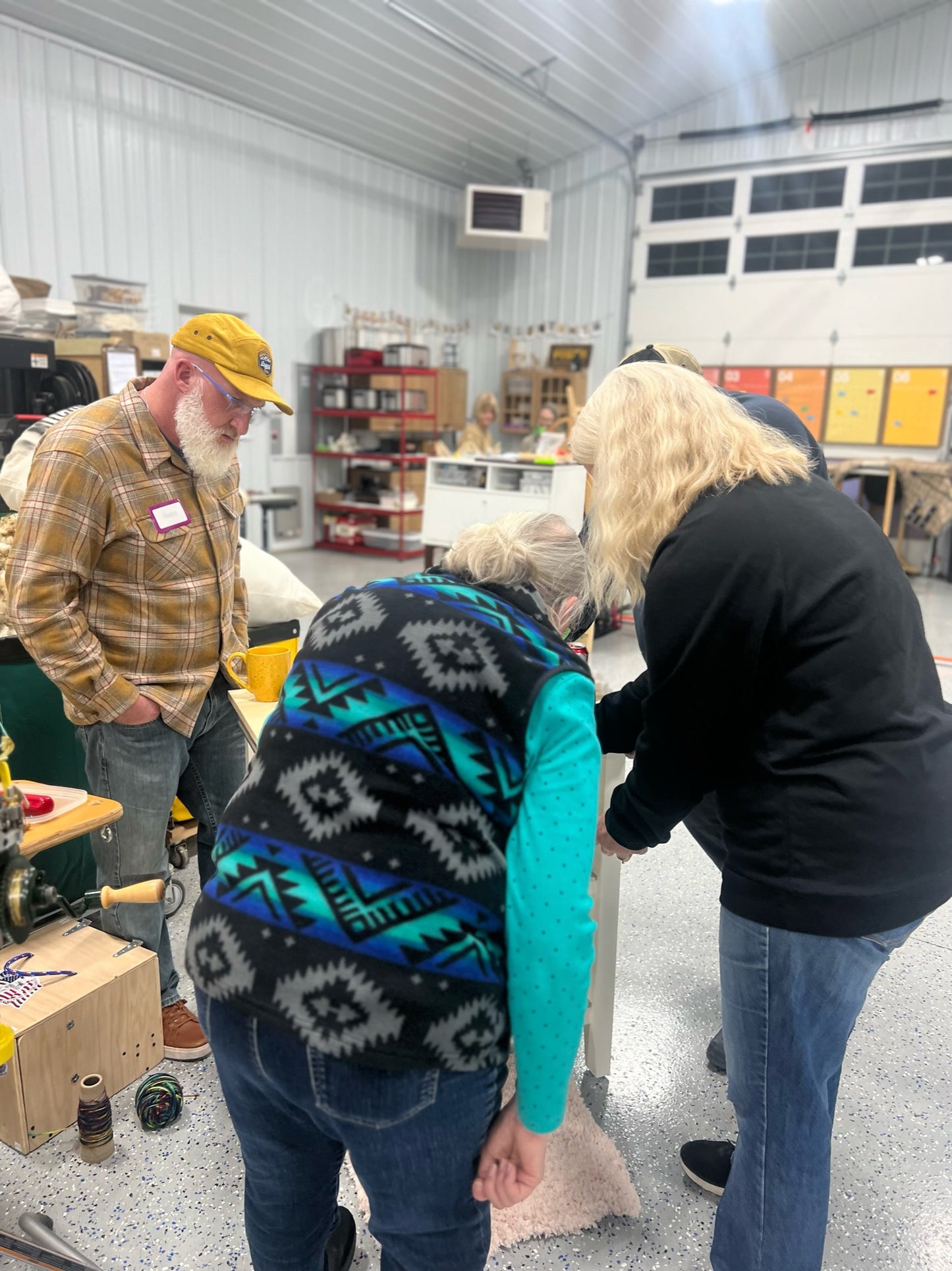 Three humans stand around a sock machine