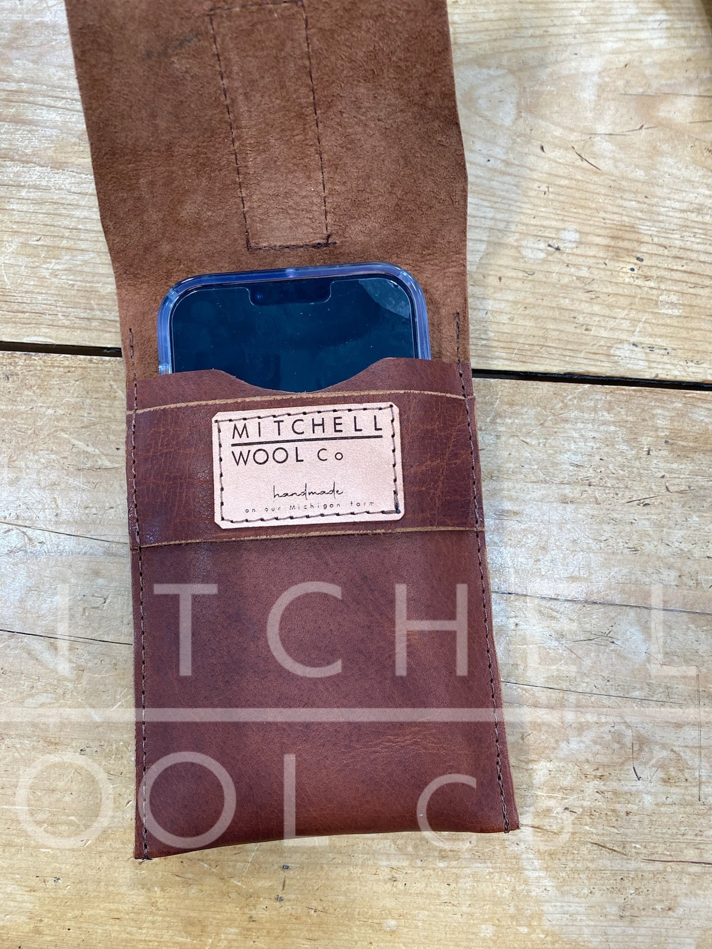 image of brown leather cellphone pouch open with an iPhone inside